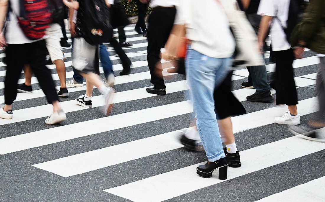 Pedestrians crossing a city street at a marked crosswalk