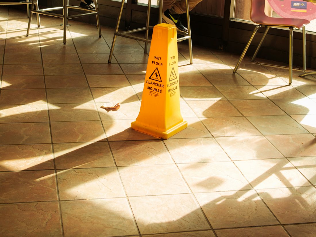 A yellow wet floor caution sign on a tiled floor